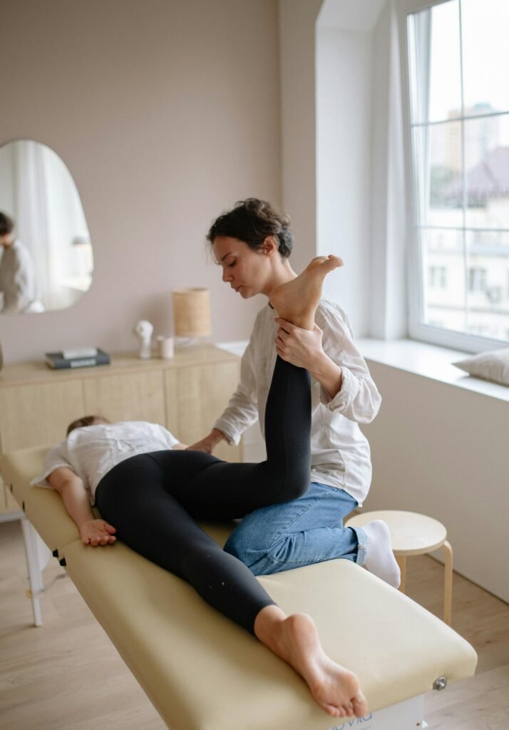 pexels-photo-5794025-5794025 Physiotherapist aiding a woman with leg exercises on a massage table for relaxation and therapy.