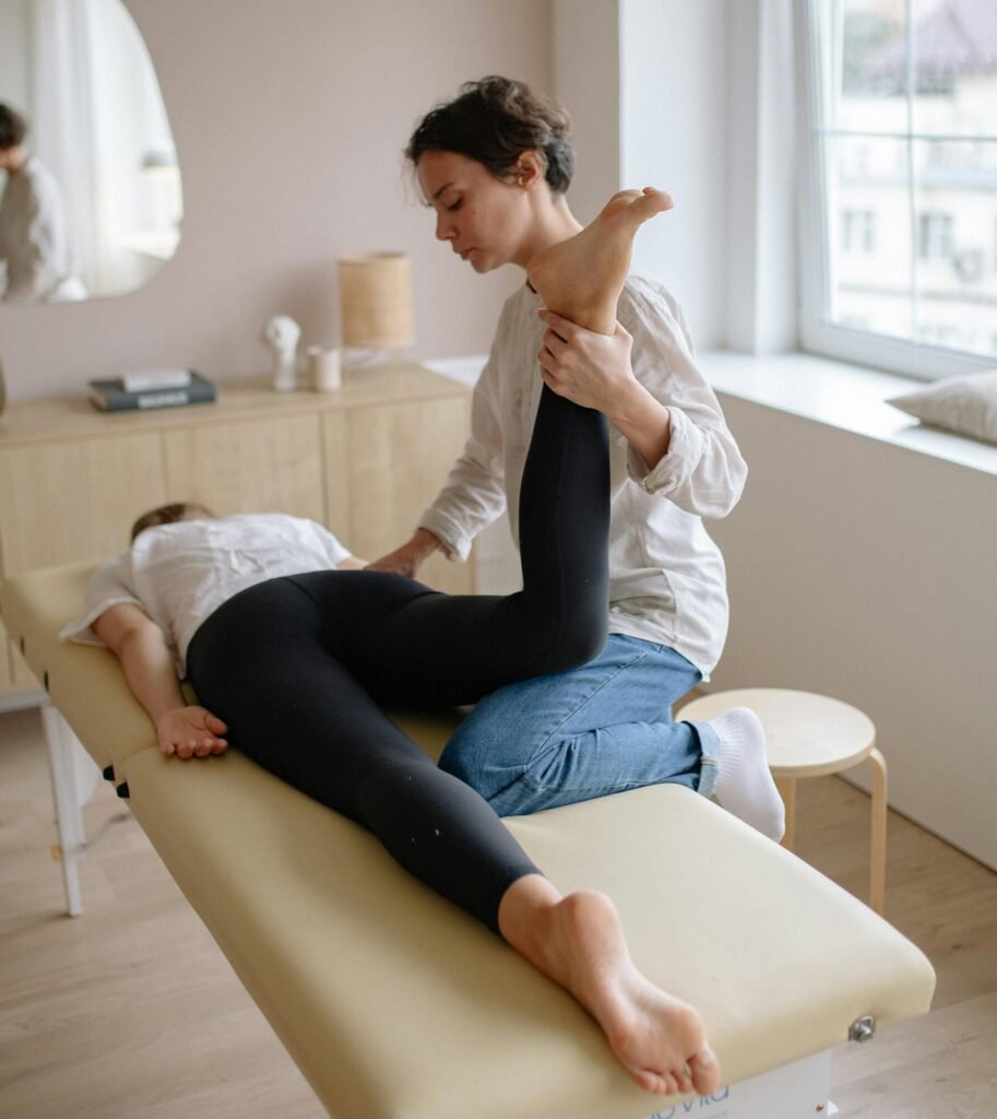 pexels-photo-5794025-5794025 Physiotherapist aiding a woman with leg exercises on a massage table for relaxation and therapy.